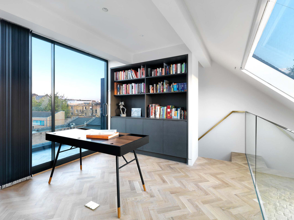 Inspiration for a contemporary home office in London with white walls, no fireplace, a library, light hardwood floors, a freestanding desk and beige floor.