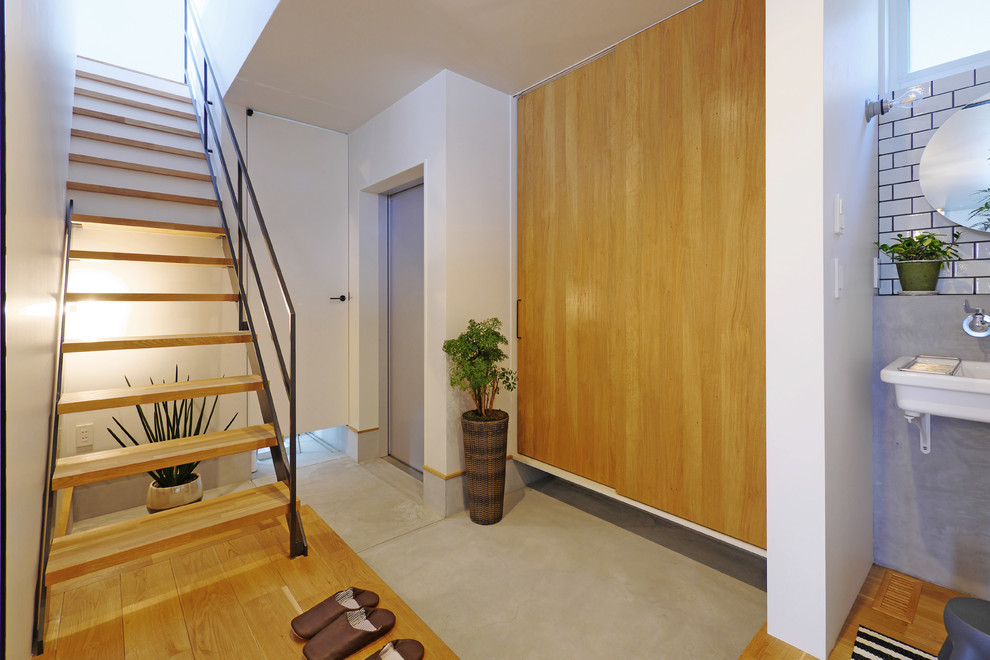 This is an example of a modern entry hall in Other with white walls, medium hardwood floors and a metal front door.