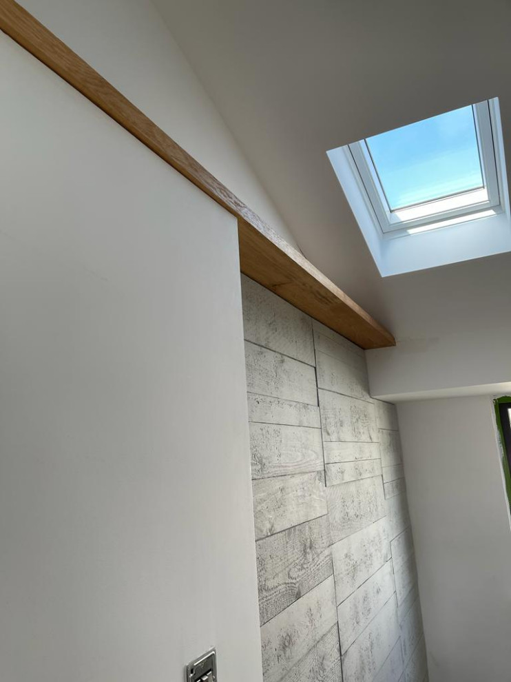 Photo of a contemporary mezzanine bedroom in Kent with white walls, light hardwood flooring, a vaulted ceiling, panelled walls and a feature wall.