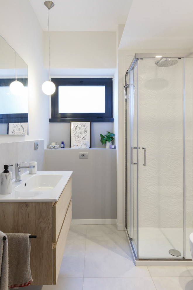 Inspiration for a small modern shower room bathroom in Rome with flat-panel cabinets, light wood cabinets, a corner shower, a two-piece toilet, grey tiles, porcelain tiles, white walls, porcelain flooring, an integrated sink, grey floors, a sliding door, a single sink, a floating vanity unit and a drop ceiling.