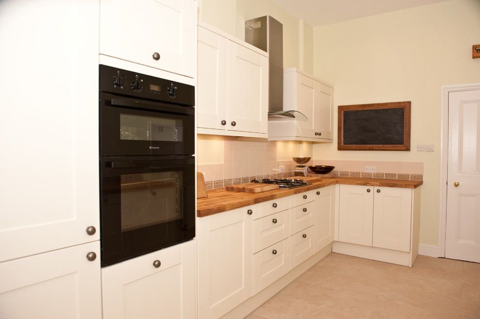 Photo of a large modern galley eat-in kitchen in London with a drop-in sink, flat-panel cabinets, white cabinets, wood benchtops, multi-coloured splashback, ceramic splashback, stainless steel appliances, ceramic floors and no island.