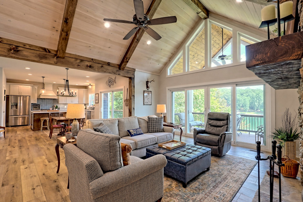 Inspiration for a large arts and crafts open concept living room in Atlanta with grey walls, laminate floors, a standard fireplace, a built-in media wall, brown floor and exposed beam.