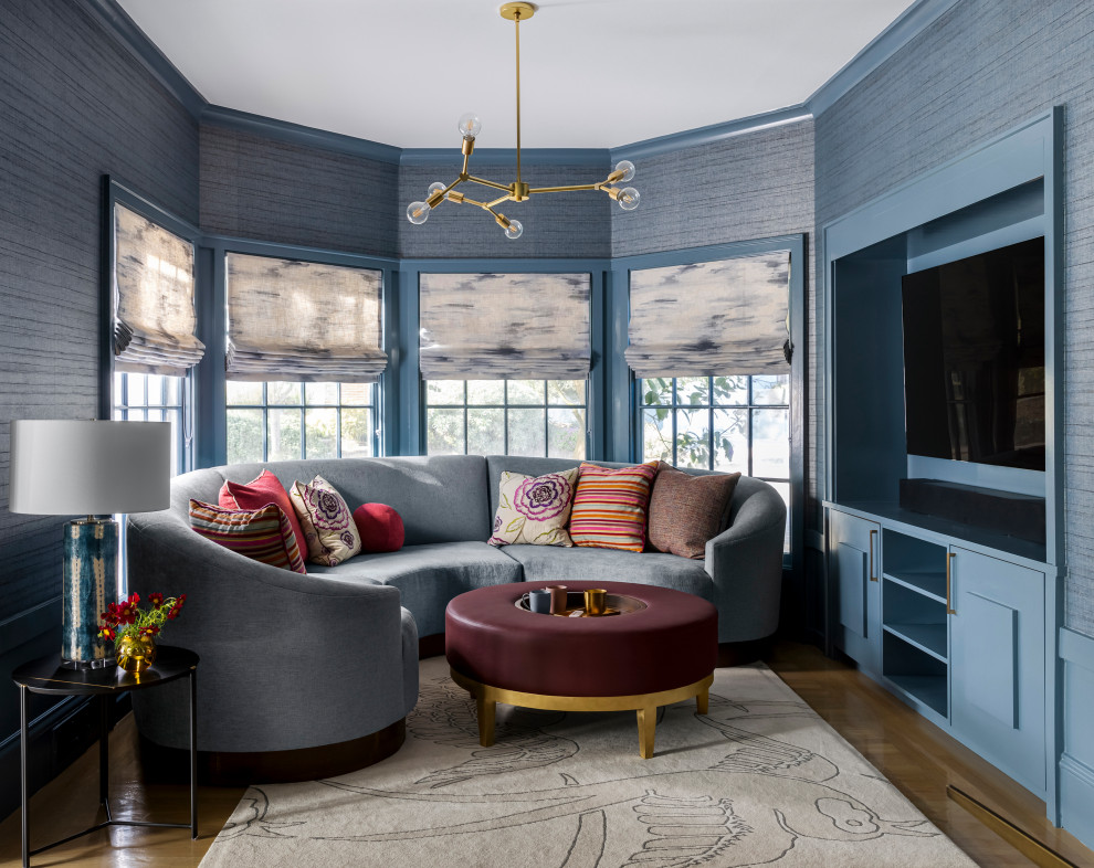 Photo of a mid-sized transitional open concept family room in San Francisco with blue walls, light hardwood floors, a built-in media wall and beige floor.