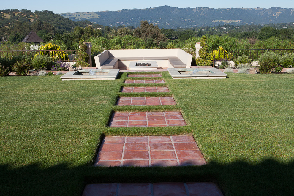 This is an example of a large transitional backyard patio in San Francisco with a fire feature, tile and no cover.