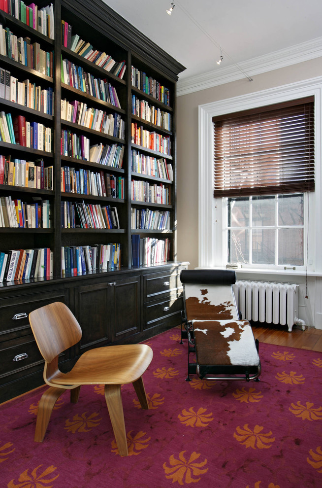 This is an example of an eclectic family room in Boston with a library, beige walls and medium hardwood floors.