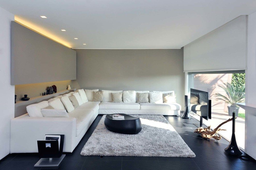 Large contemporary open concept family room in Milan with grey walls and a freestanding tv.