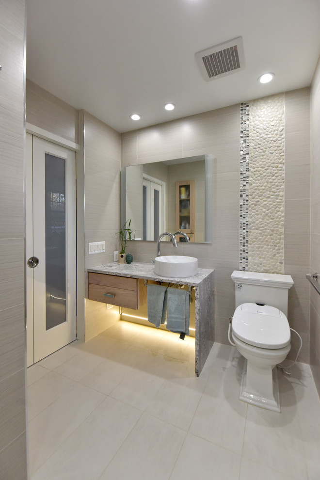 Transitional bathroom in DC Metro with open cabinets, beige tile, black and white tile, pebble tile, beige walls, a vessel sink and grey floor.