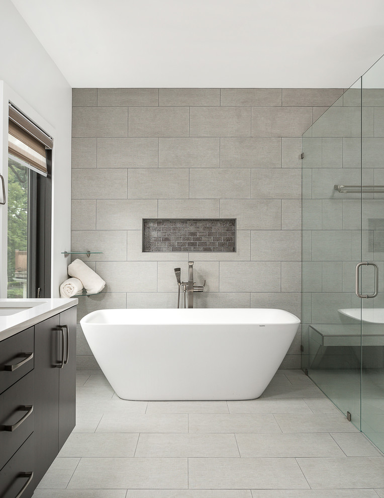 Inspiration for a large contemporary master bathroom in Chicago with flat-panel cabinets, black cabinets, a freestanding tub, a curbless shower, a one-piece toilet, gray tile, porcelain tile, white walls, porcelain floors, an undermount sink, engineered quartz benchtops, grey floor, a hinged shower door and white benchtops.