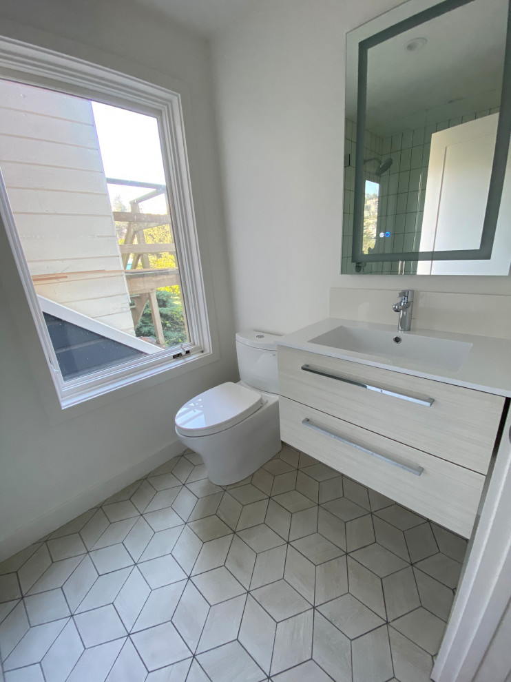 This is an example of a mid-sized contemporary bathroom in San Francisco with flat-panel cabinets, light wood cabinets, an alcove shower, a two-piece toilet, white tile, ceramic tile, white walls, porcelain floors, an integrated sink, engineered quartz benchtops, beige floor, a hinged shower door, white benchtops, a single vanity and a floating vanity.