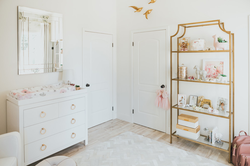 Small transitional nursery in Los Angeles with light hardwood floors, white walls and beige floor for girls.