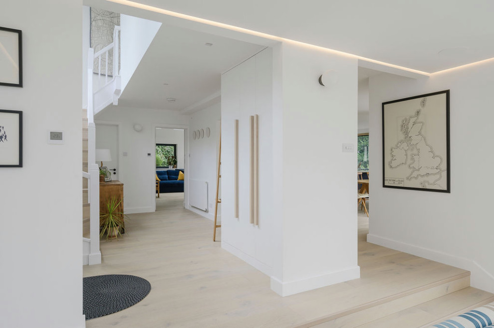 Inspiration för mellanstora moderna hallar, med vita väggar, ljust trägolv och vitt golv