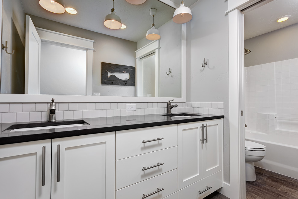 Photo of a mid-sized country kids bathroom in Boise with an undermount sink, recessed-panel cabinets, white cabinets, engineered quartz benchtops, an open shower, white tile, subway tile, grey walls, linoleum floors and an alcove tub.