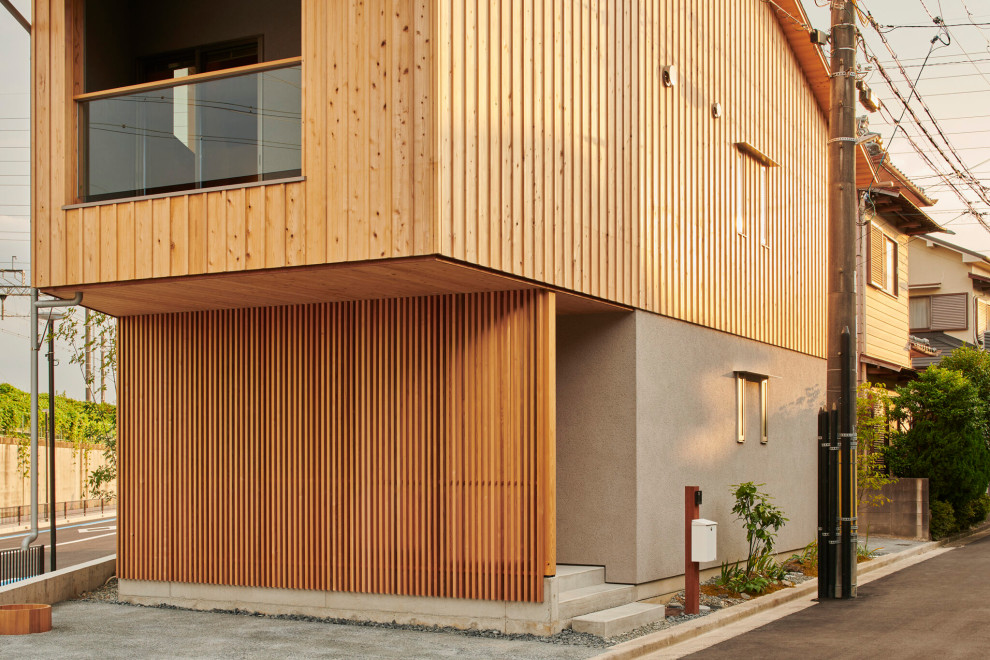 This is an example of a large country two-storey brown house exterior in Osaka with wood siding, a gable roof, a metal roof, a grey roof and board and batten siding.