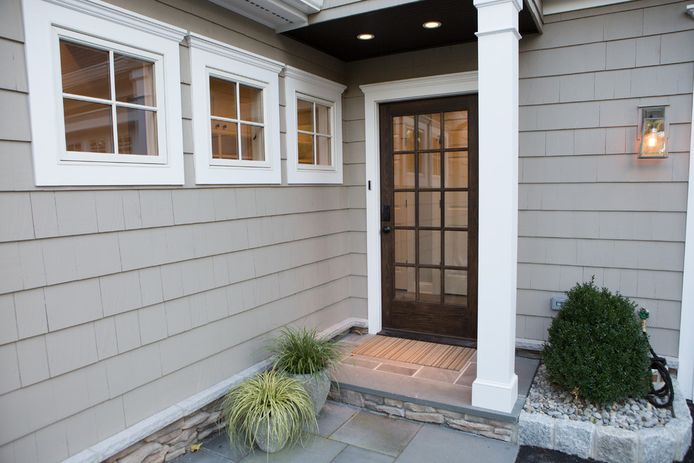 This is an example of a large traditional split-level grey exterior in New York with wood siding and a shed roof.