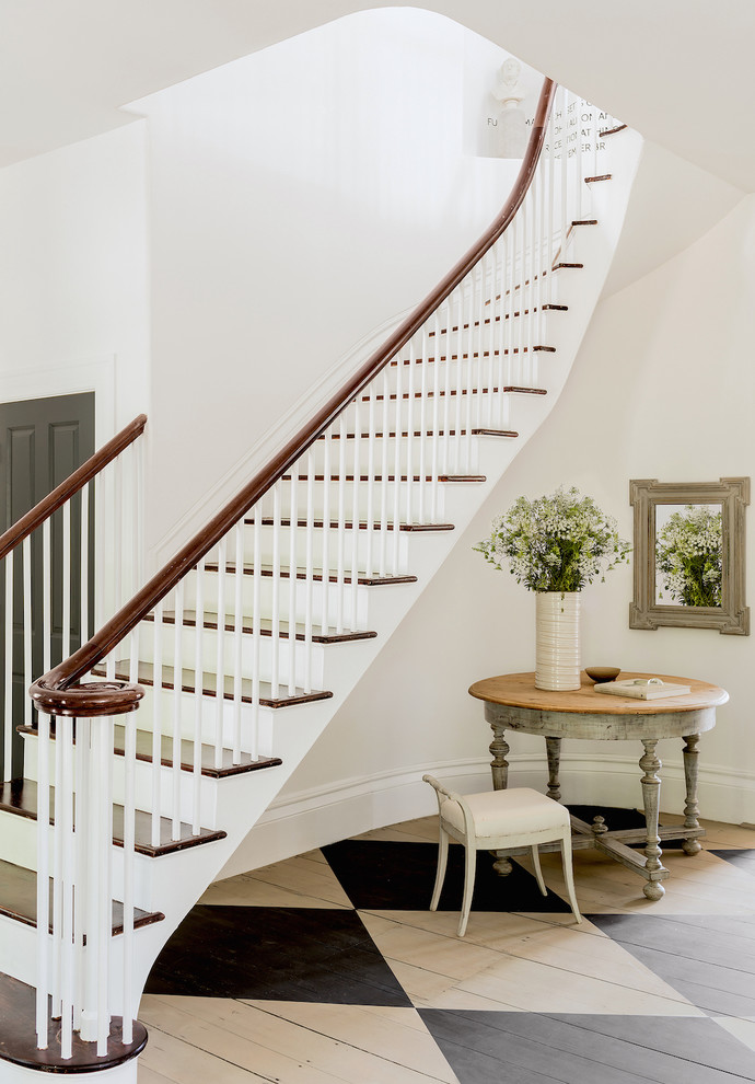 This is an example of a beach style wood curved staircase with wood railing and painted wood risers.