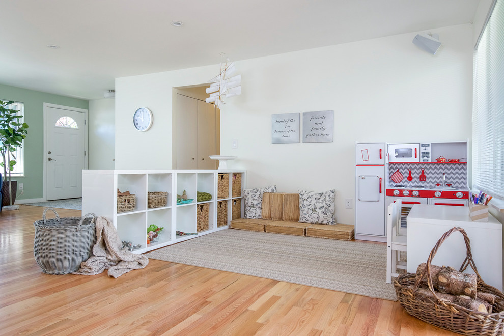 Photo of a mid-sized transitional kids' room for girls in Seattle with white walls and light hardwood floors.