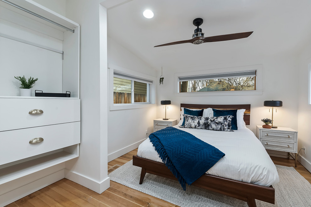 Kleines Mid-Century Hauptschlafzimmer mit weißer Wandfarbe, braunem Holzboden und braunem Boden in Boise