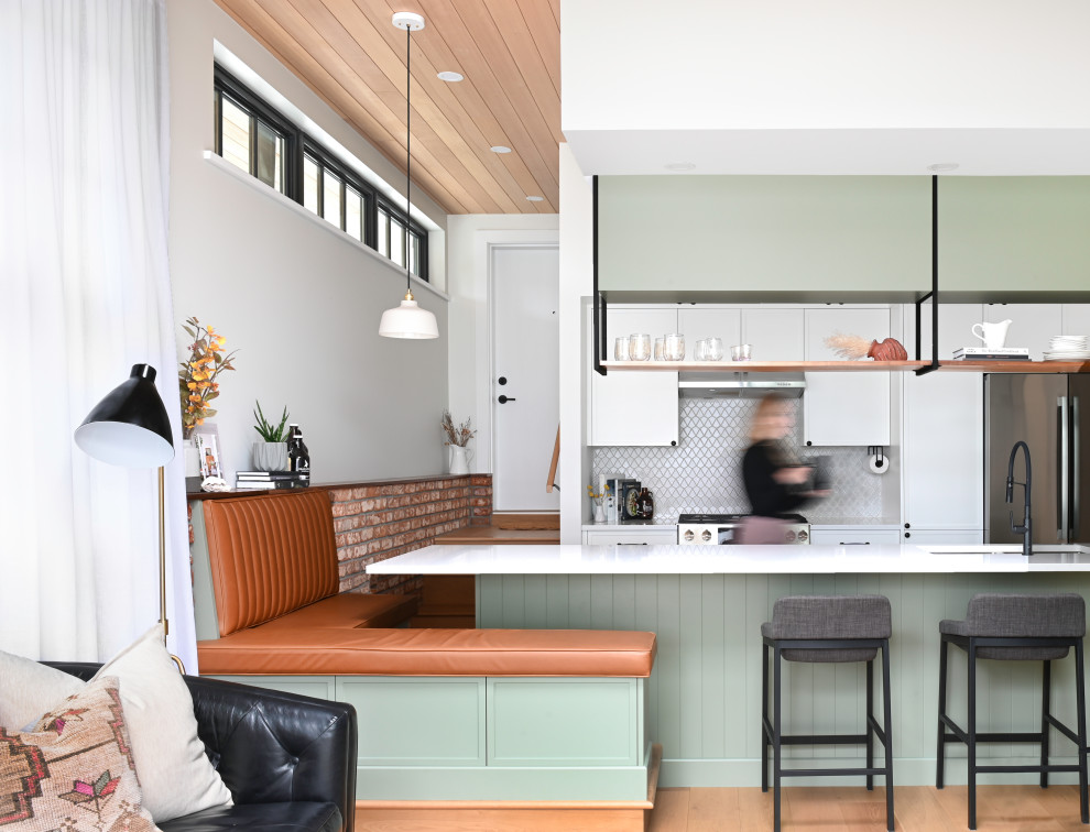 Modern inredning av ett litet vit vitt kök, med en undermonterad diskho, skåp i shakerstil, gröna skåp, bänkskiva i kvarts, grått stänkskydd, stänkskydd i keramik, rostfria vitvaror, ljust trägolv, en köksö och beiget golv