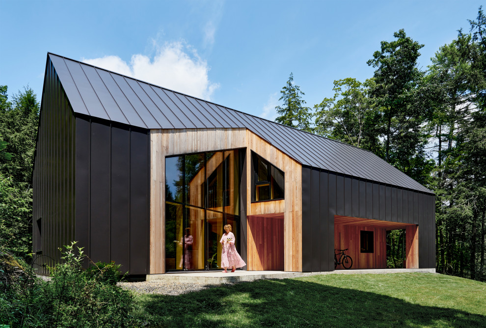 На фото: одноэтажный, черный частный загородный дом в скандинавском стиле с облицовкой из металла, металлической крышей и черной крышей с