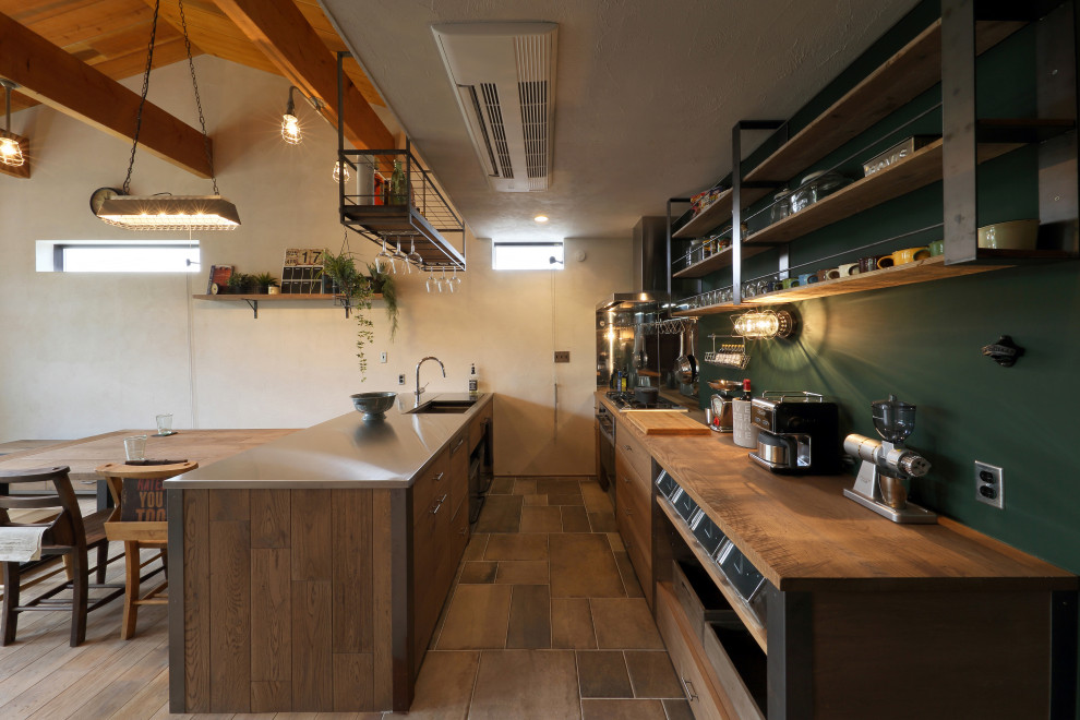 This is an example of an industrial kitchen in Other with a double-bowl sink, open cabinets, wood benchtops, green splashback, a peninsula, multi-coloured floor, brown benchtop and exposed beam.