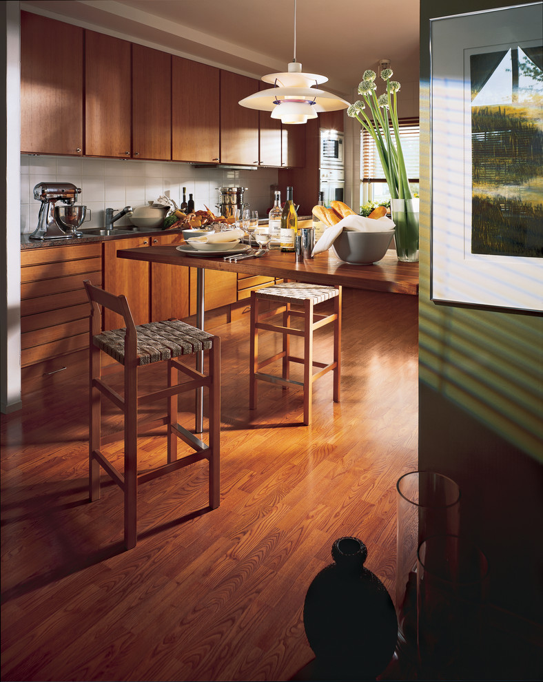 Inspiration for a small transitional medium tone wood floor kitchen remodel with a double-bowl sink, flat-panel cabinets, light wood cabinets, laminate countertops, white backsplash, ceramic backsplash and stainless steel appliances
