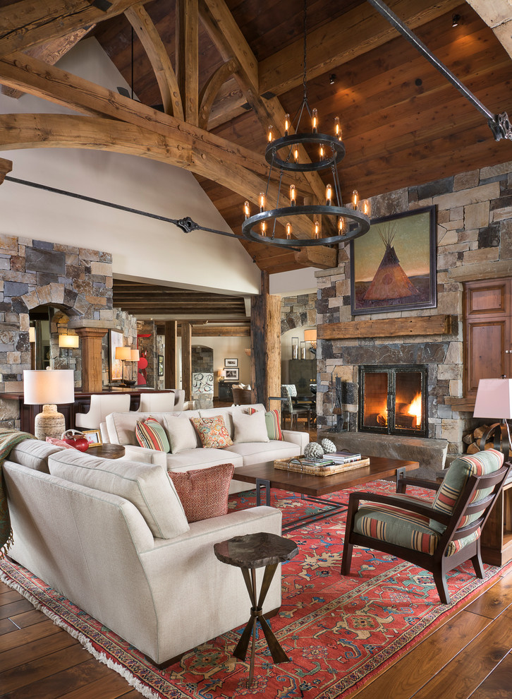 Country family room in Other with medium hardwood floors, a standard fireplace, a stone fireplace surround and a concealed tv.