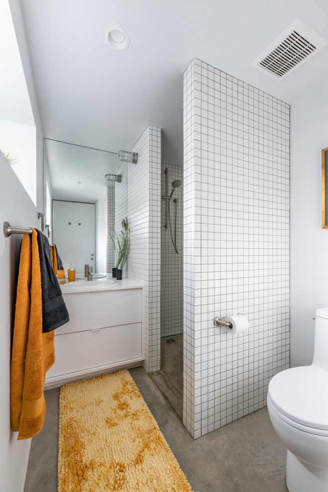 На фото: маленькая ванная комната в стиле лофт с плоскими фасадами, белыми фасадами, угловым душем, унитазом-моноблоком, белой плиткой, керамогранитной плиткой, белыми стенами, бетонным полом, накладной раковиной, столешницей из ламината, открытым душем, белой столешницей, тумбой под одну раковину и встроенной тумбой для на участке и в саду