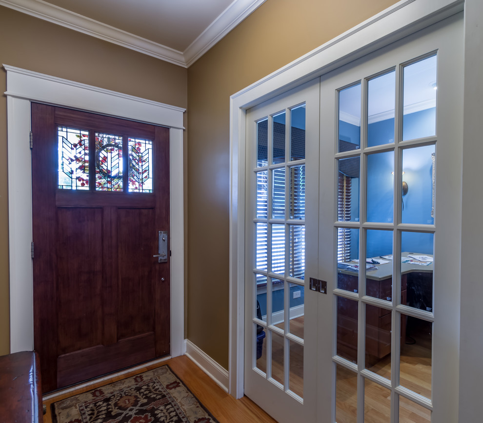 Inspiration for a small traditional entry hall in Chicago with brown walls, light hardwood floors, a single front door, a medium wood front door, brown floor, wallpaper and wallpaper.