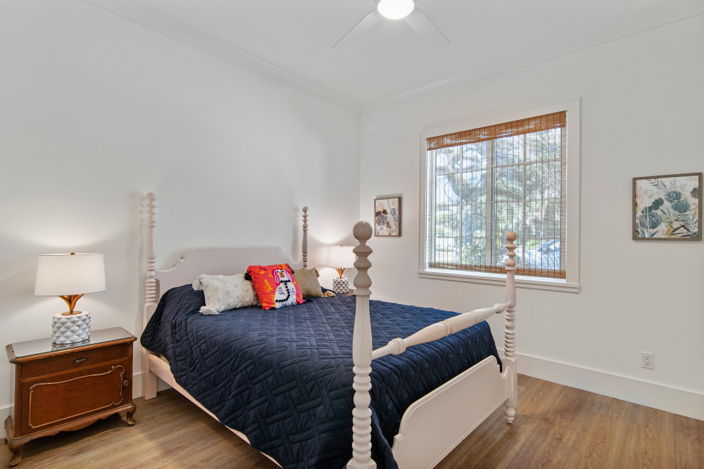 Modelo de habitación de invitados costera grande con paredes blancas, suelo vinílico y suelo beige