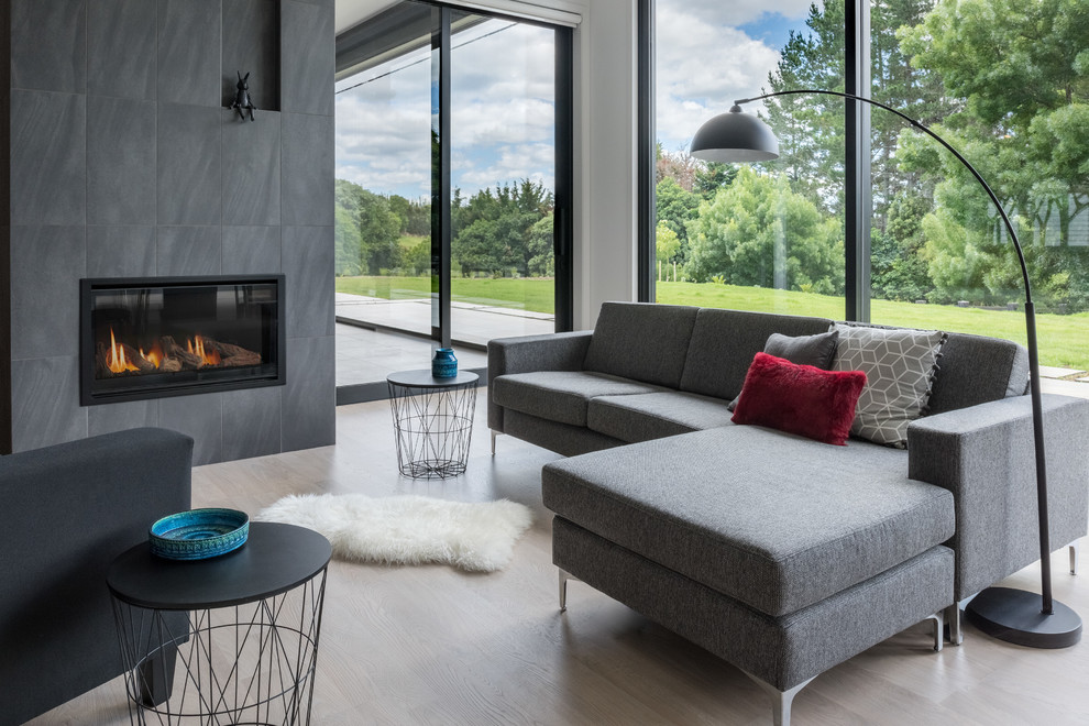 Inspiration for a contemporary open concept living room in Other with white walls, light hardwood floors, a standard fireplace, a tile fireplace surround and black floor.