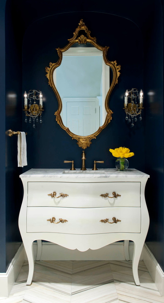 Photo of a traditional powder room in Dallas with an undermount sink, furniture-like cabinets, white cabinets, marble benchtops, beige tile and blue walls.