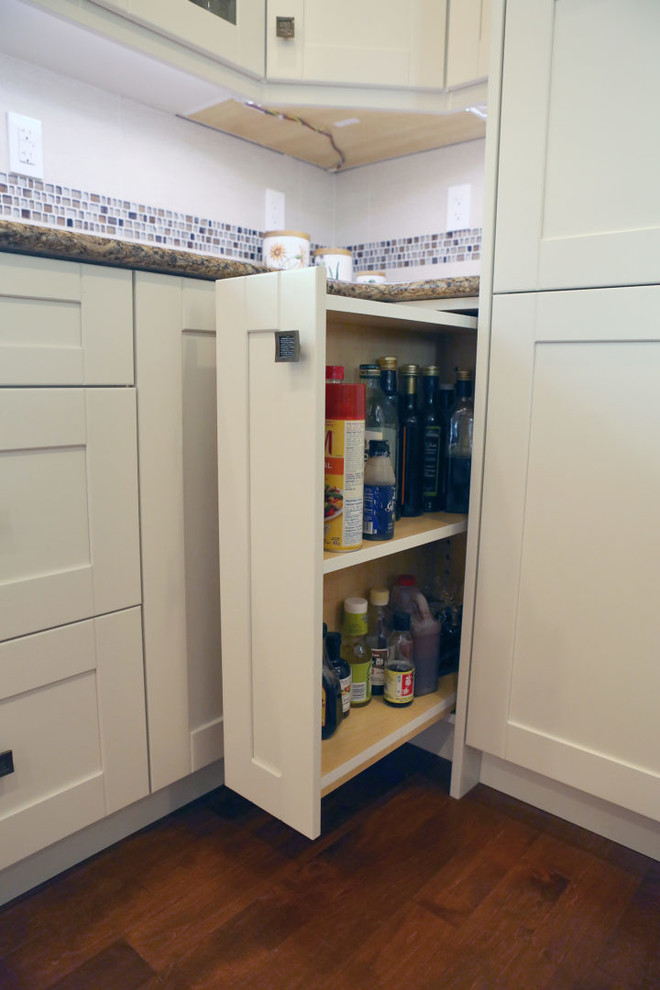 Mid-sized transitional l-shaped medium tone wood floor and brown floor open concept kitchen photo in Calgary with an undermount sink, shaker cabinets, white cabinets, granite countertops, white backsplash, mosaic tile backsplash, stainless steel appliances, an island and beige countertops