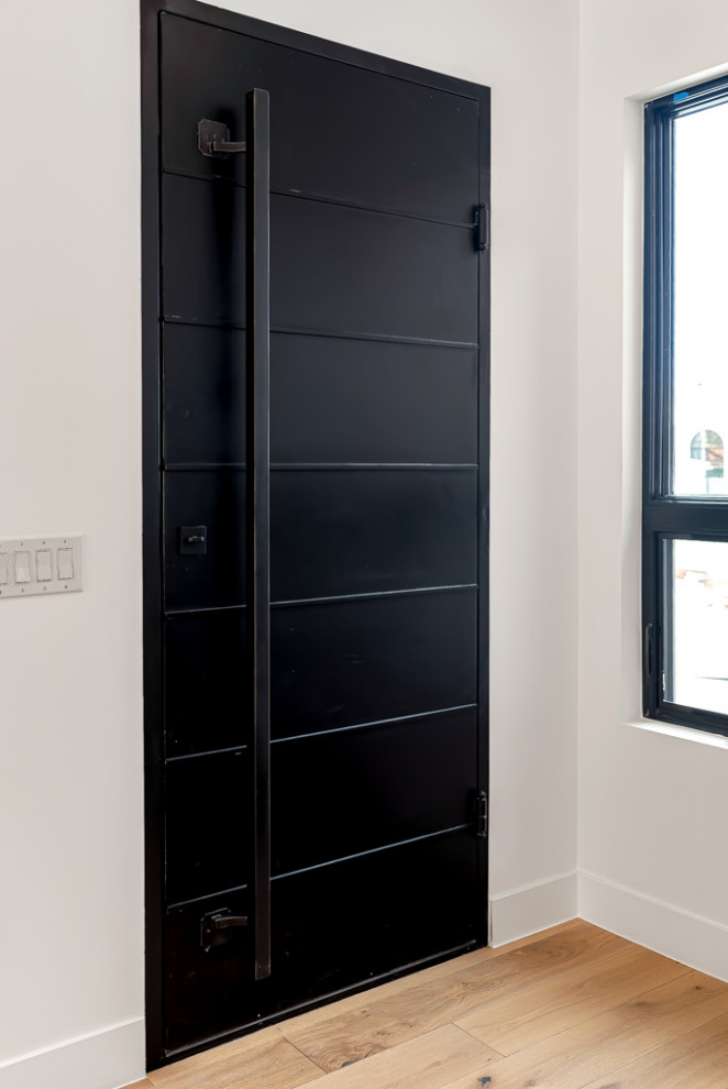 Идея дизайна: большая узкая прихожая в стиле модернизм с белыми стенами, светлым паркетным полом, одностворчатой входной дверью, черной входной дверью и коричневым полом