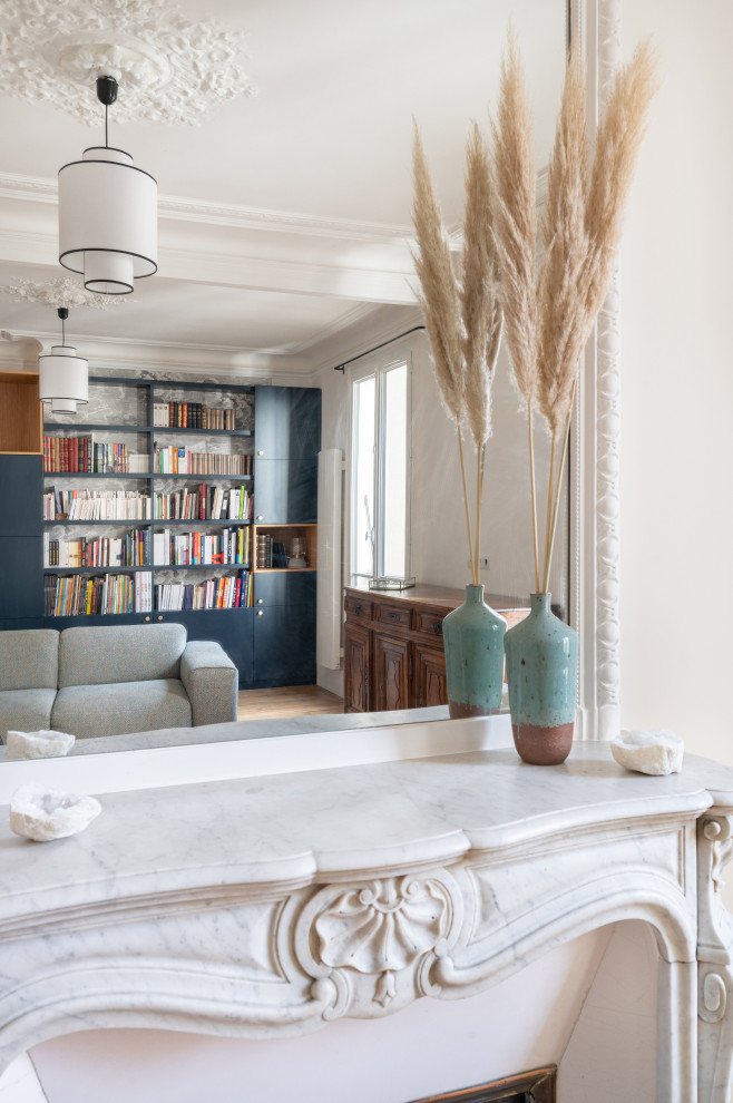Idée de décoration pour un grand salon design fermé et haussmannien avec une bibliothèque ou un coin lecture, un mur blanc, parquet clair et une cheminée standard.