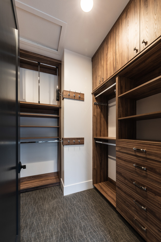 Photo of a mid-sized contemporary women's walk-in wardrobe in Salt Lake City with flat-panel cabinets, medium wood cabinets, carpet and grey floor.
