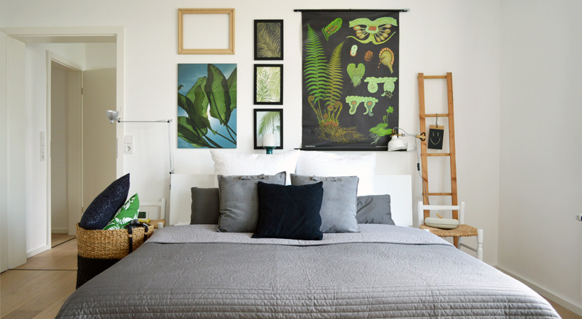 Ejemplo de habitación de invitados urbana de tamaño medio sin chimenea con paredes blancas y suelo de madera en tonos medios