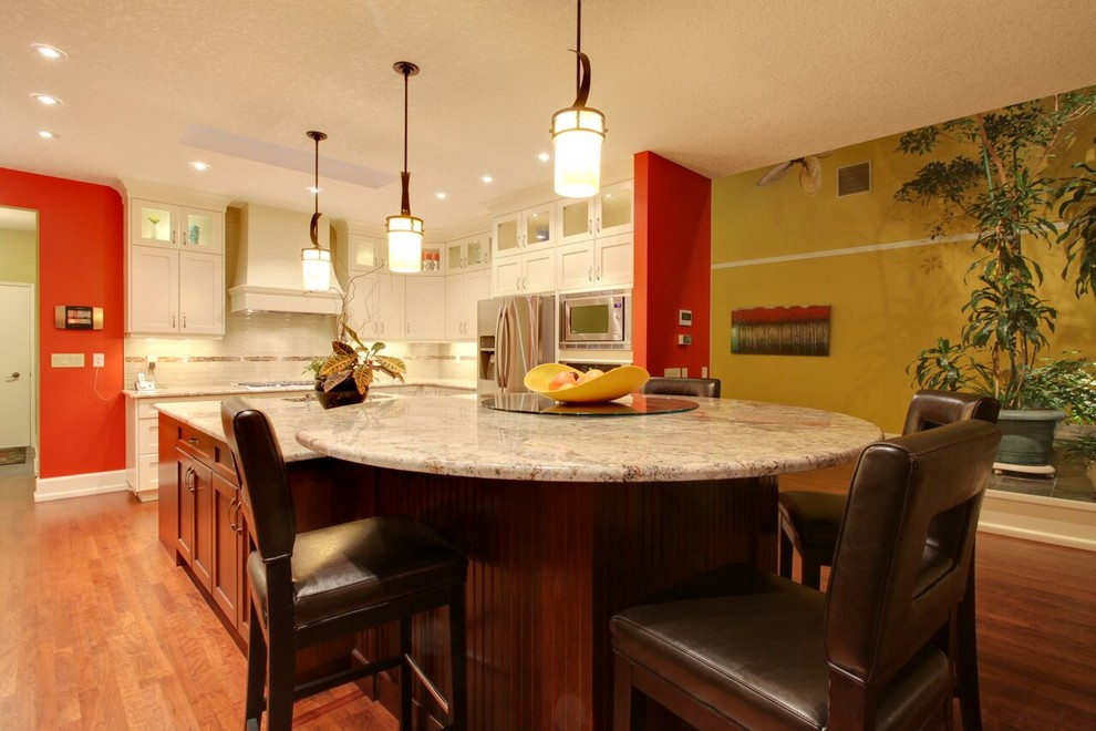Large transitional l-shaped medium tone wood floor and brown floor open concept kitchen photo in Calgary with an undermount sink, recessed-panel cabinets, white cabinets, glass countertops, beige backsplash, matchstick tile backsplash, stainless steel appliances and an island