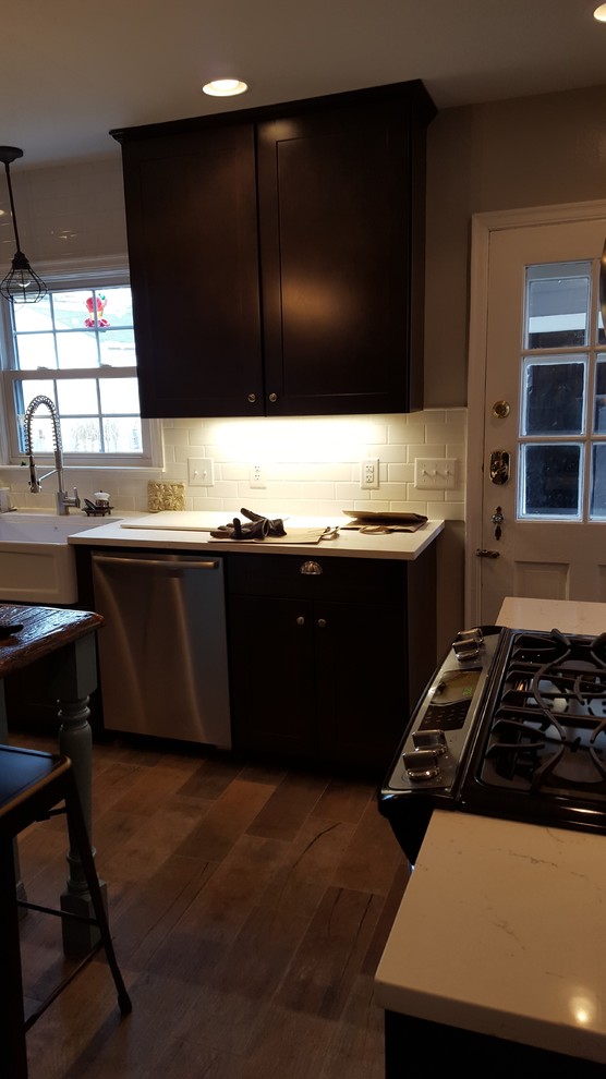 Example of a mid-sized mountain style u-shaped porcelain tile eat-in kitchen design in Indianapolis with a farmhouse sink, shaker cabinets, dark wood cabinets, wood countertops, white backsplash, ceramic backsplash, stainless steel appliances and an island