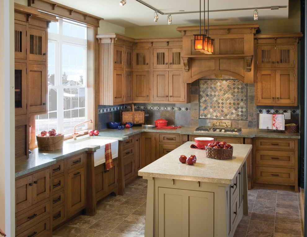 Photo of a mid-sized arts and crafts l-shaped kitchen in Chicago with a farmhouse sink, shaker cabinets, medium wood cabinets, multi-coloured splashback, stone tile splashback, ceramic floors, with island and brown floor.