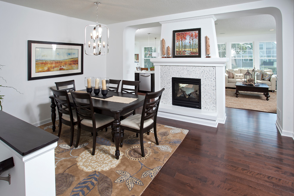 Design ideas for a transitional dining room in Minneapolis with white walls, dark hardwood floors, a two-sided fireplace and a tile fireplace surround.
