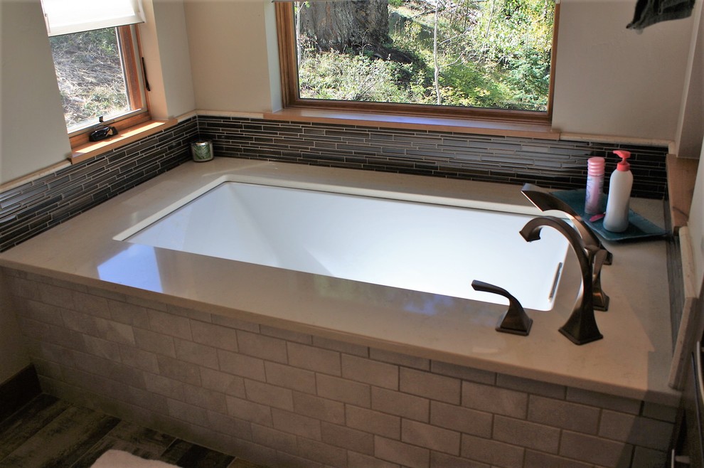 Large mountain style master brown floor bathroom photo with an undermount tub and quartz countertops