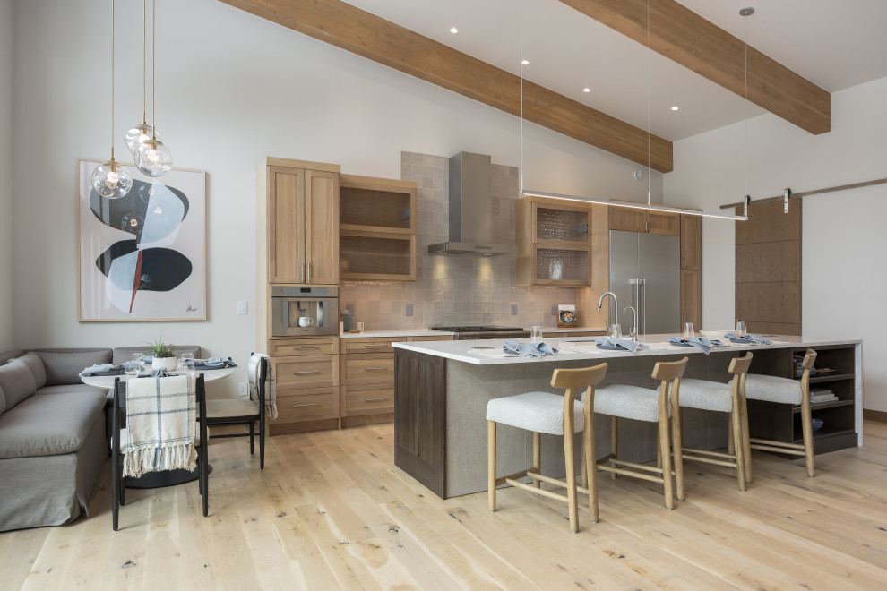 Eat-in kitchen - transitional galley light wood floor, beige floor, exposed beam and vaulted ceiling eat-in kitchen idea in Denver with an undermount sink, shaker cabinets, light wood cabinets, gray backsplash, stainless steel appliances, an island and white countertops
