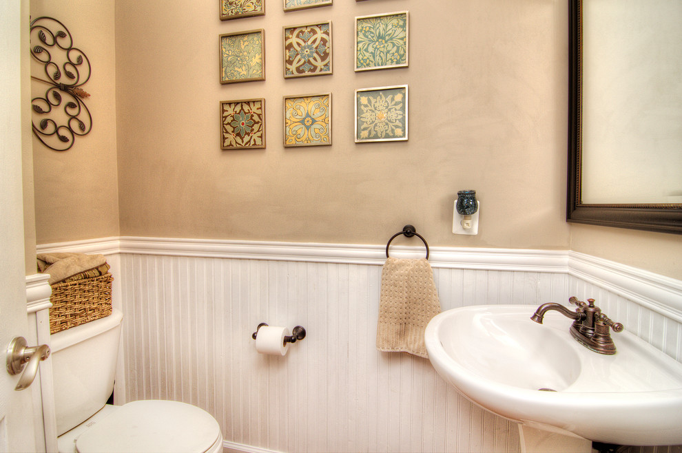 Mid-sized beach style powder room in Charlotte with a pedestal sink, beige walls and medium hardwood floors.