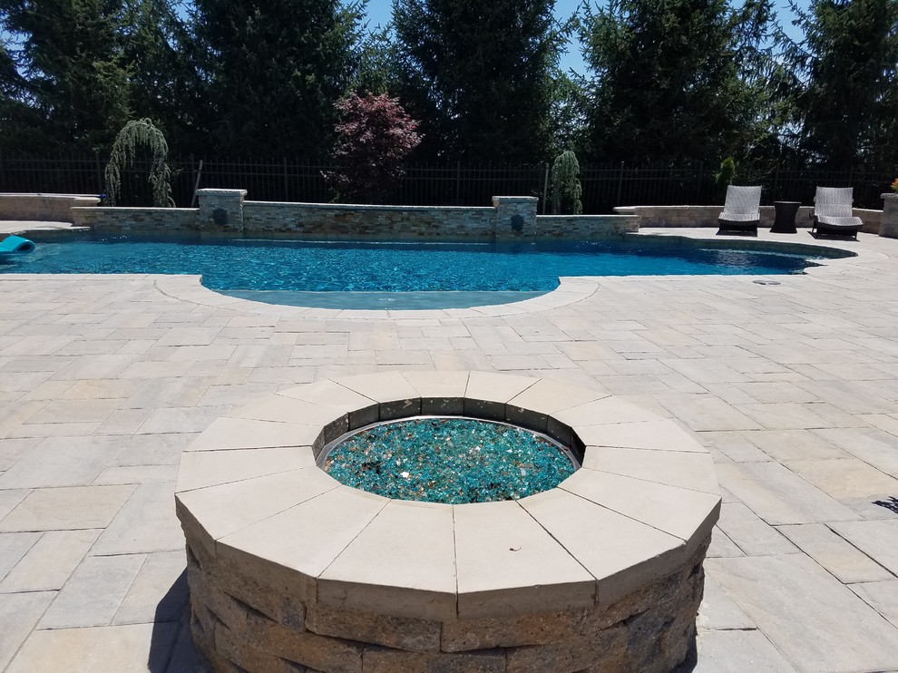 This is an example of a large mediterranean backyard custom-shaped natural pool in Baltimore with a water feature and concrete pavers.