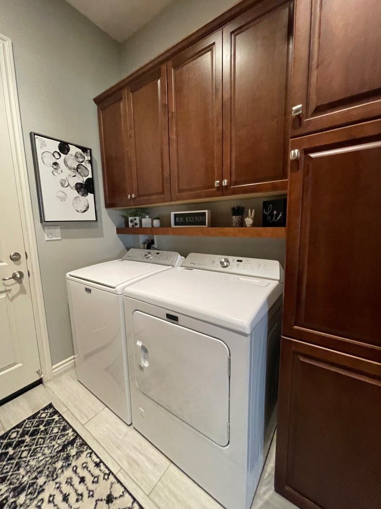 Immagine di una sala lavanderia tradizionale di medie dimensioni con ante con bugna sagomata, ante marroni, pareti grigie, pavimento in travertino, lavatrice e asciugatrice affiancate e pavimento marrone