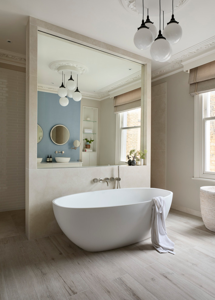 This is an example of an expansive contemporary master wet room bathroom in London with white cabinets, a freestanding tub, a wall-mount toilet, white tile, ceramic tile, blue walls, porcelain floors, a vessel sink, engineered quartz benchtops, grey floor, an open shower, white benchtops, a double vanity, a freestanding vanity and wallpaper.
