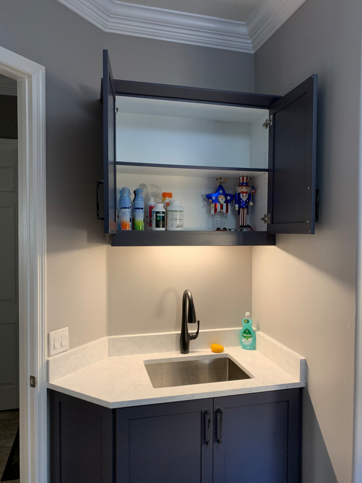 This is an example of a medium sized contemporary single-wall separated utility room in Orlando with a submerged sink, shaker cabinets, grey cabinets, engineered stone countertops, white splashback, engineered quartz splashback, grey walls, porcelain flooring, a stacked washer and dryer, multi-coloured floors and white worktops.