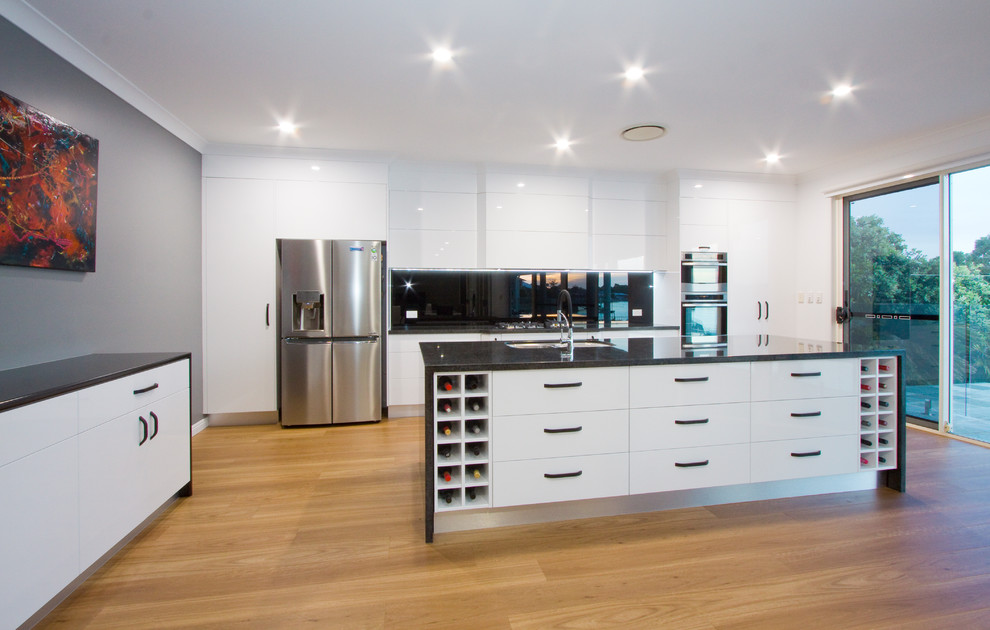 Inspiration for a large modern galley open plan kitchen in Sunshine Coast with an undermount sink, granite benchtops, mirror splashback, stainless steel appliances, with island and black benchtop.