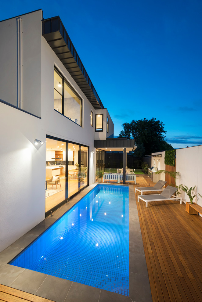 Contemporary side yard rectangular lap pool in Melbourne with tile.