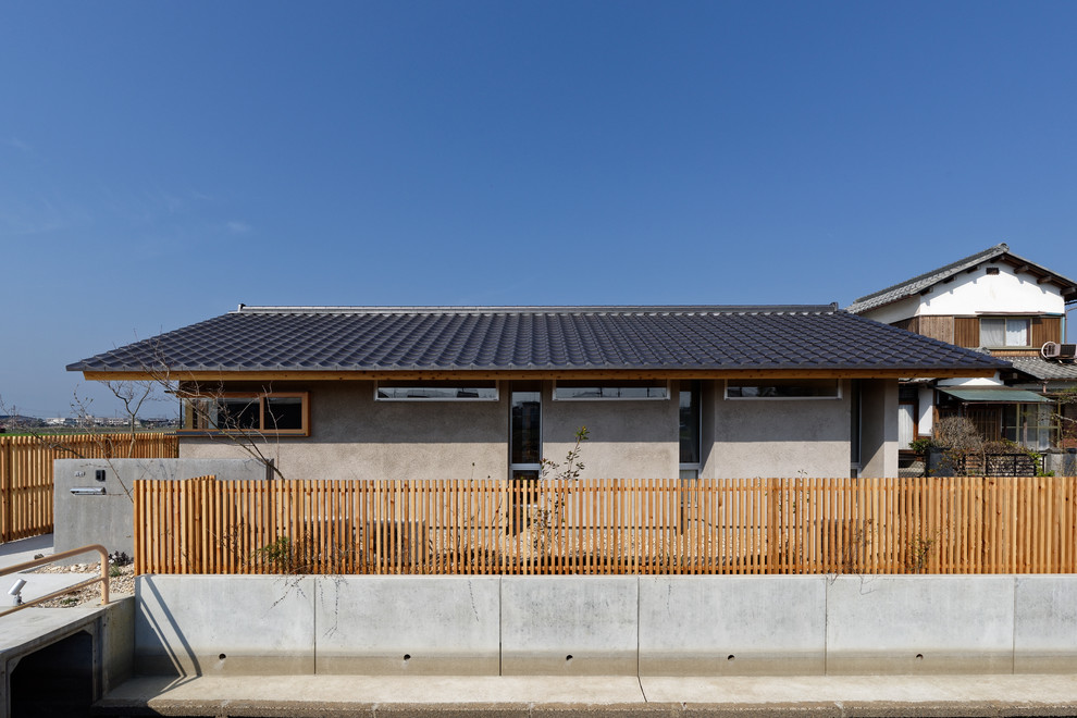 This is an example of an asian one-storey grey house exterior in Kyoto with a gable roof and a tile roof.